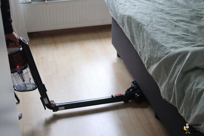 Man sieht den Shark Anti Hair Wrap Flexoloxy bei der Reinigung unter Möbeln.